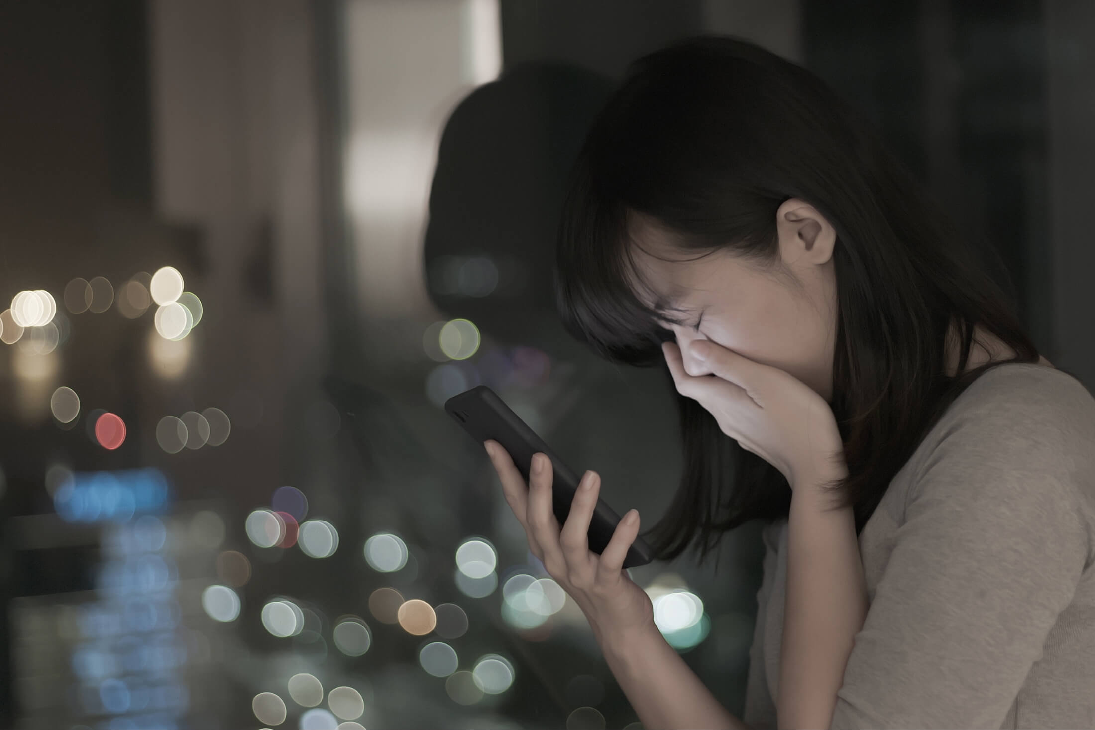 Distressed woman holding cell phone in one hand and with one hand over her mouth